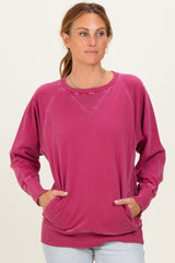 woman wearing a pink oversized sweater with raglan sleeves and side pockets, styled casually with light wash jeans
