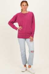 woman wearing a fuchsia oversized sweatshirt with ribbed cuffs and distressed light blue jeans