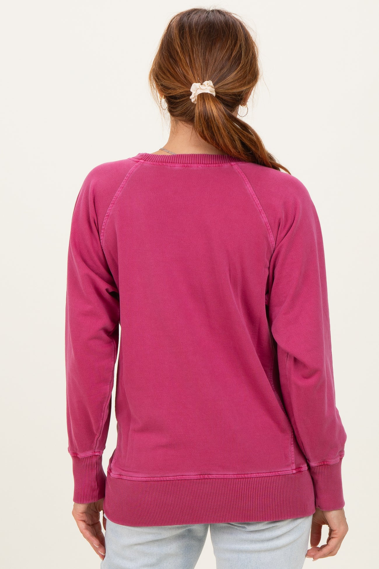 woman wearing a pink sweatshirt with a relaxed fit and ribbed hem, viewed from the back