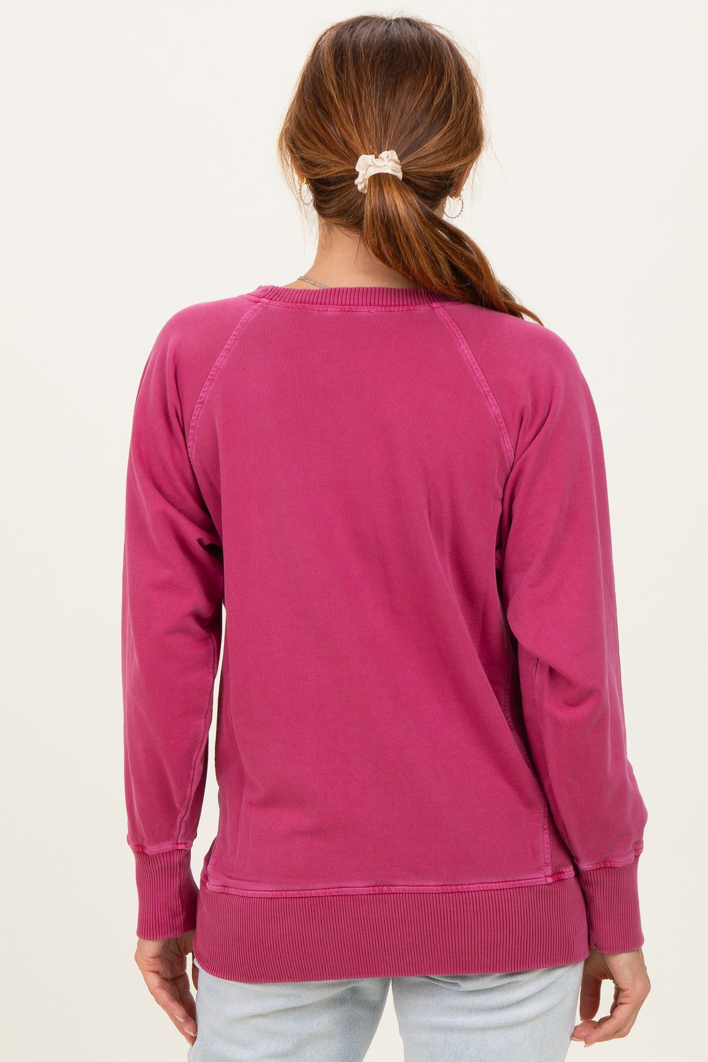 woman wearing a pink sweatshirt with a relaxed fit and ribbed hem, viewed from the back