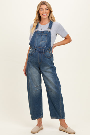 woman wearing a blue denim maternity overall with a relaxed fit and a light gray t-shirt underneath