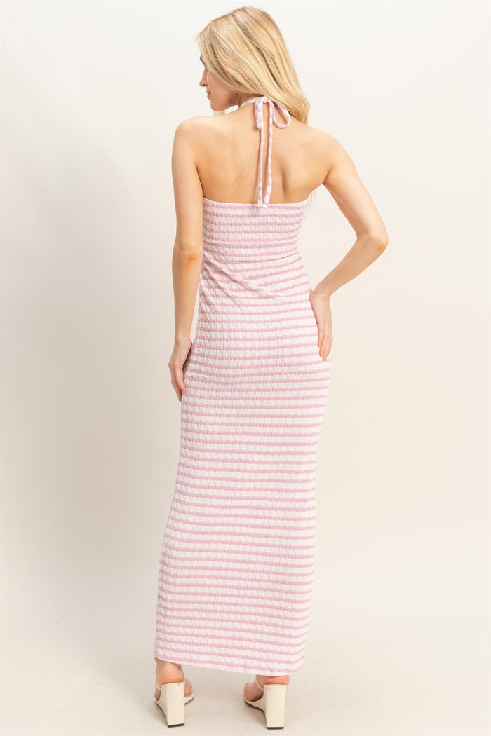 woman wearing a pink and white striped maxi dress with a halter neck and fitted style, viewed from the back