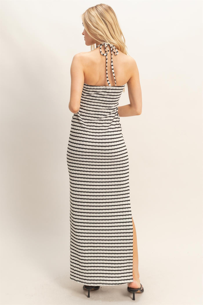 woman wearing a black and white striped maxi dress with a halter neck and back tie detail