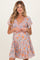 woman wearing a floral maternity dress with a v-neckline and short flutter sleeves, showcasing her baby bump