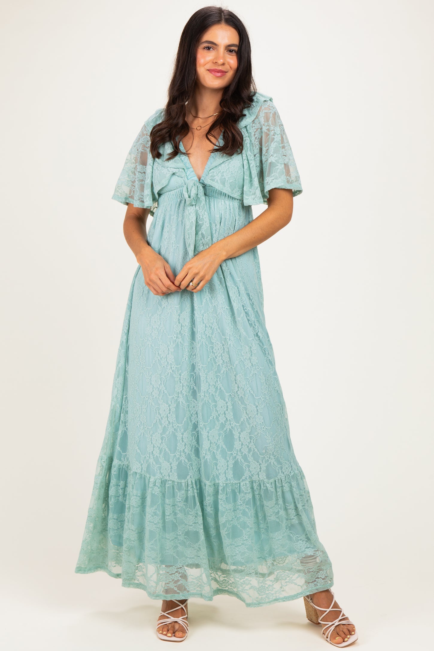 woman wearing a light teal lace maxi dress with flutter sleeves and a tie front detail