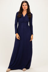 woman wearing a navy blue long sleeve maxi dress with a wrap design and empire waist