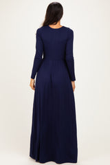 woman wearing a long navy blue maxi dress with long sleeves and a fitted bodice, showing the back view