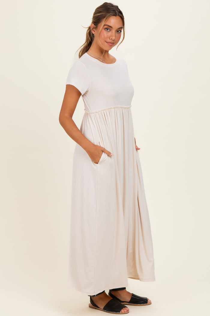 woman wearing a beige short sleeve maxi dress with a gathered waist and pockets, styled casually