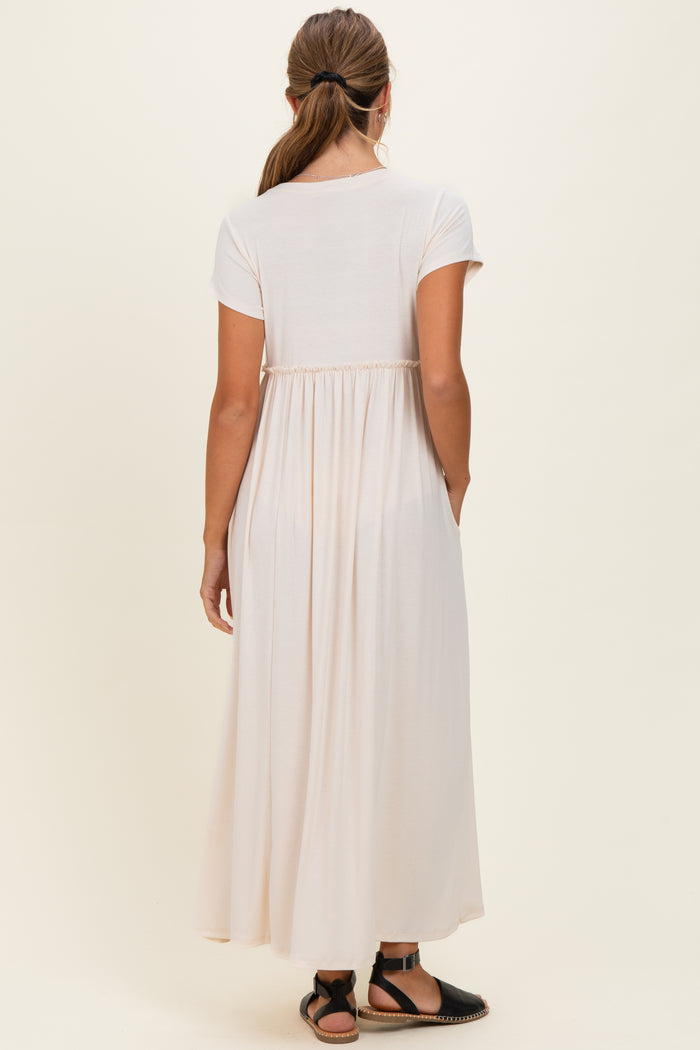 woman wearing a light pink short sleeve maxi dress with a gathered back and side pockets