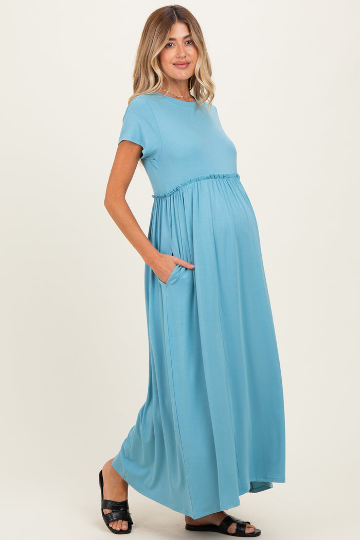 woman wearing a blue short sleeve maternity maxi dress with pockets and a visible baby bump