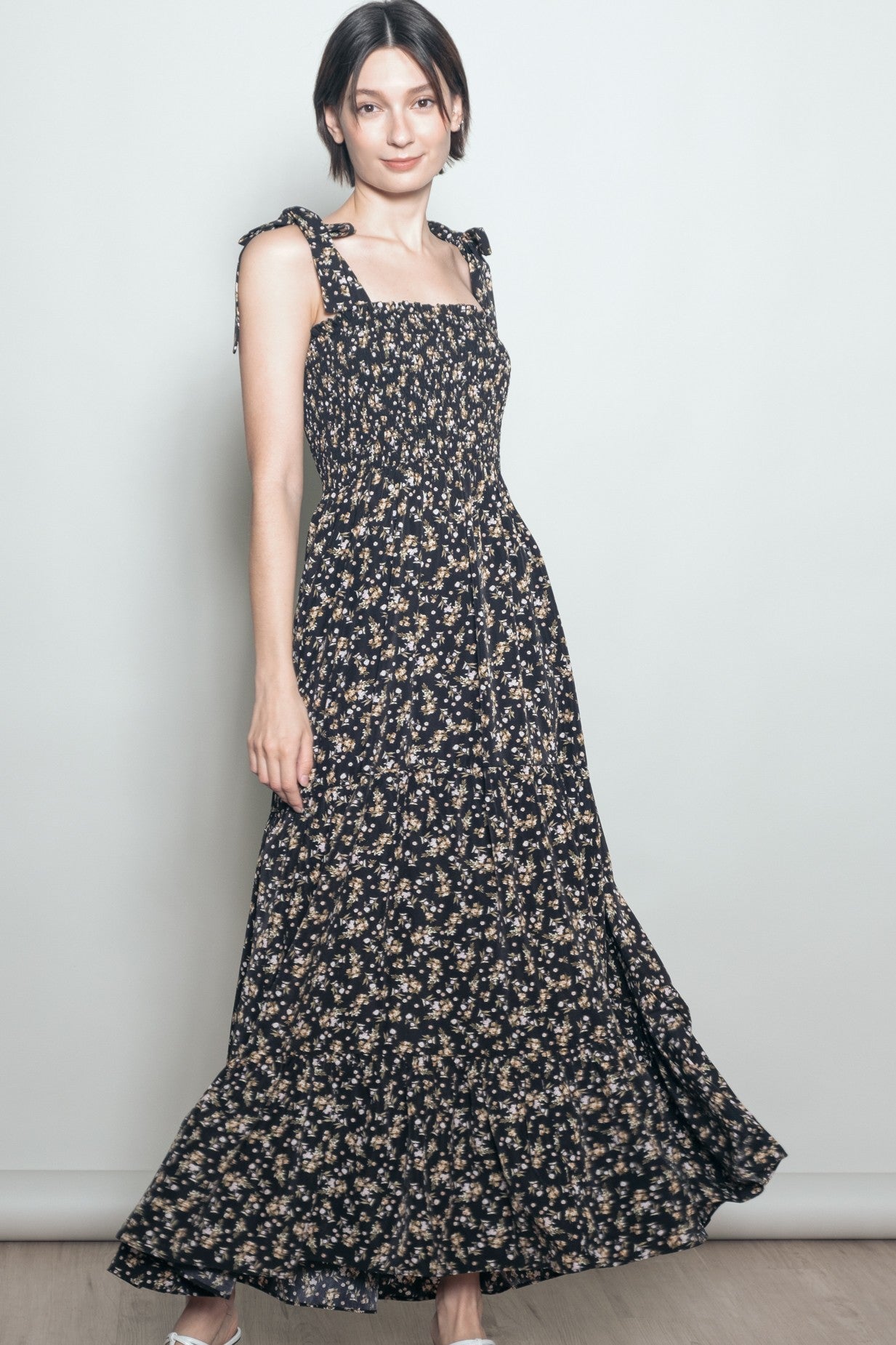 woman wearing a black floral maxi dress with ruffled straps and a fitted bodice