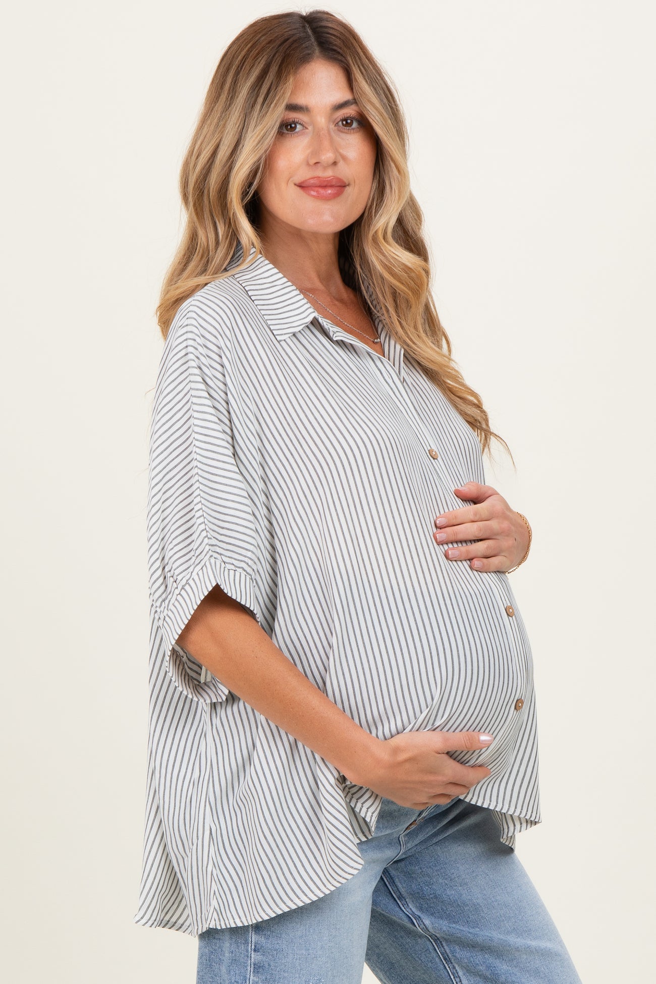 woman wearing a striped oversized maternity shirt and showing her baby bump