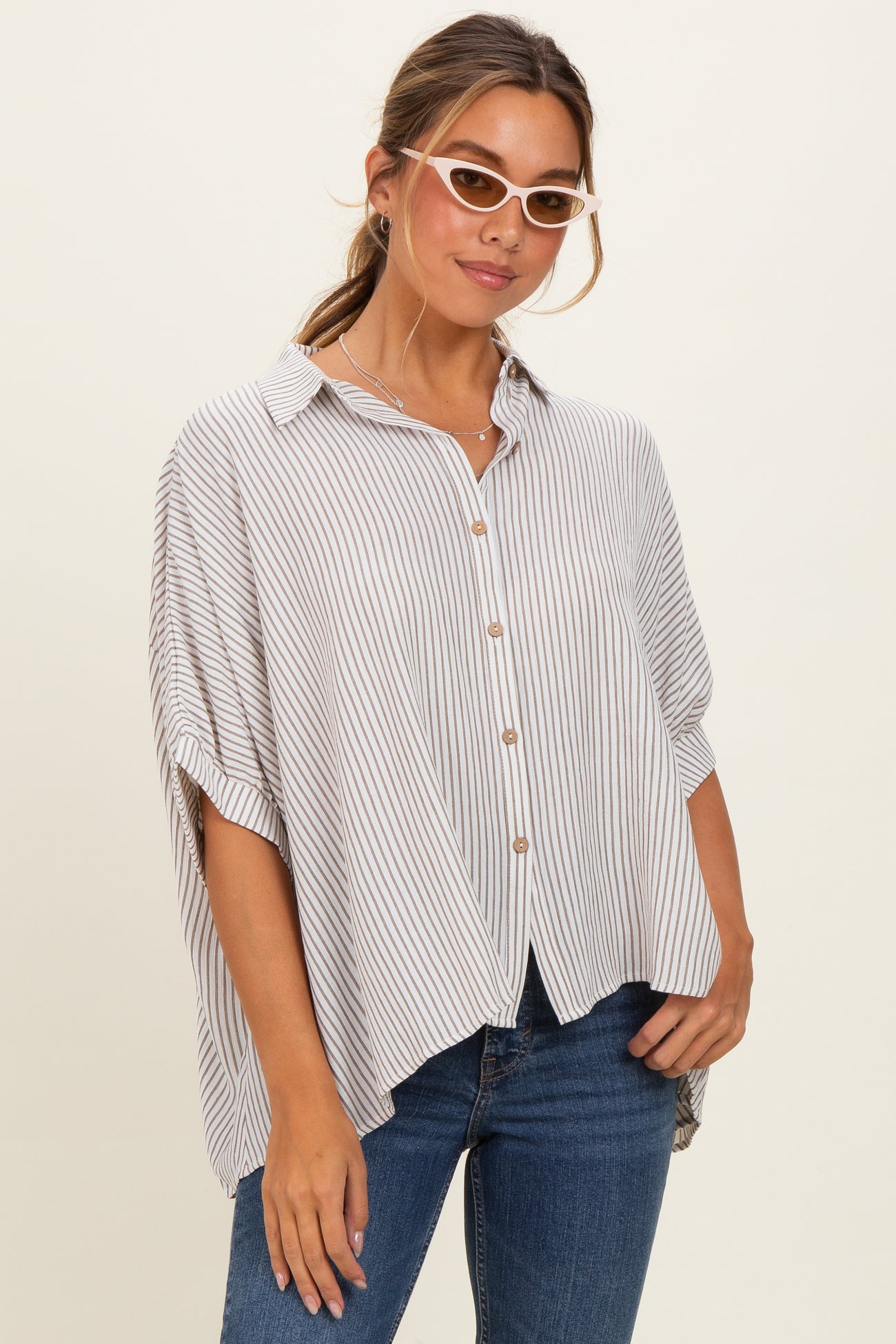 woman wearing a striped button-up shirt with rolled sleeves and a loose fit, paired with blue jeans
