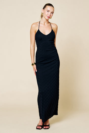 woman wearing a black halter neck maxi dress with a fitted silhouette and textured fabric