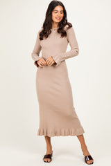 woman wearing a beige ribbed long sleeve midi dress with ruffle hem and button details on the sleeves