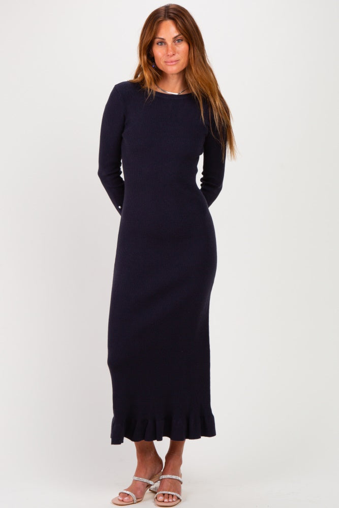 woman wearing a navy long sleeve ribbed dress with a ruffled hem and standing against a plain background