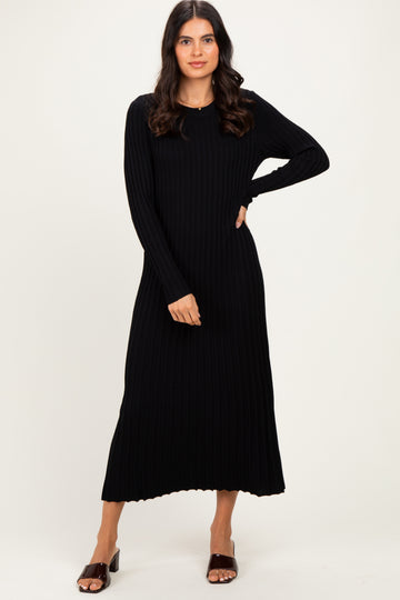 woman wearing a black ribbed long sleeve midi dress standing with one hand on her hip