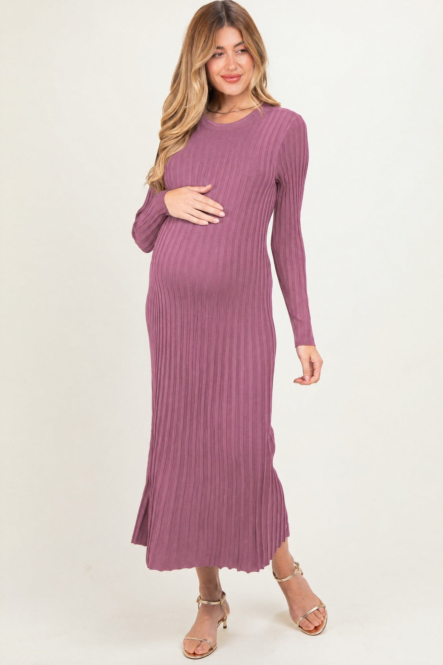 woman wearing a mauve long sleeve ribbed maternity dress and holding her baby bump