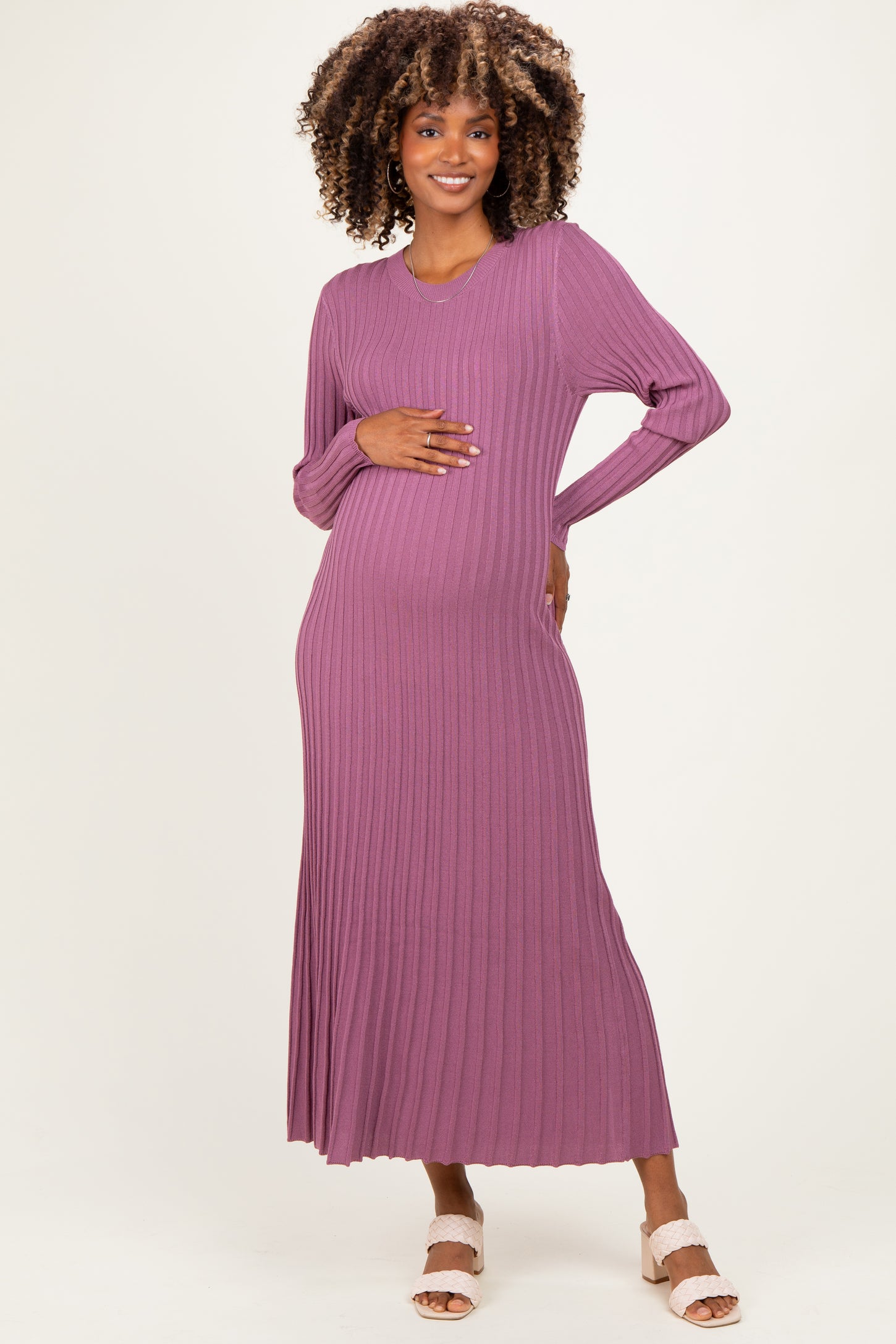 woman wearing a mauve long sleeve ribbed maternity dress, gently holding her baby bump