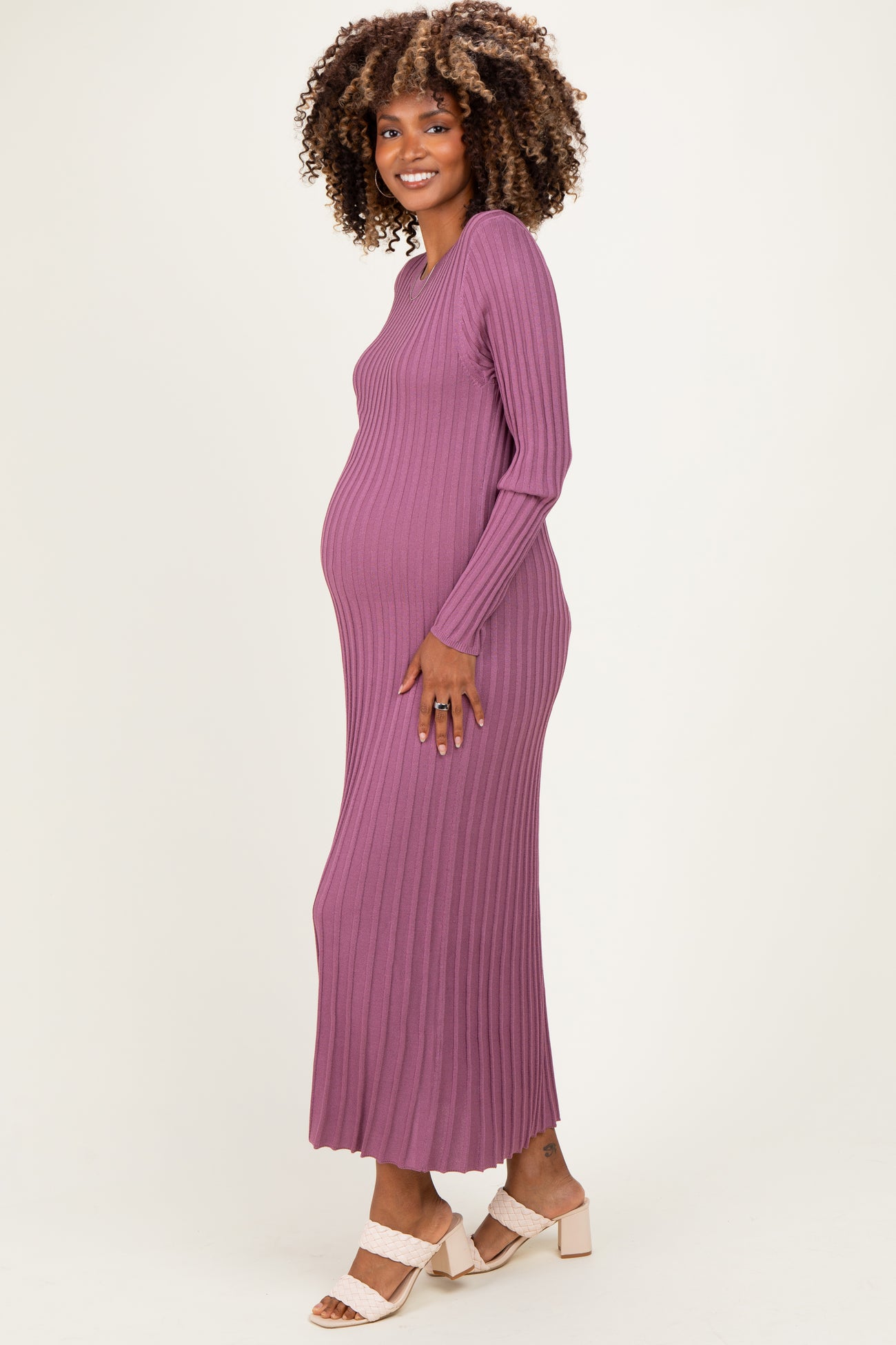 woman wearing a ribbed purple maternity maxi dress, showing her baby bump while smiling at the camera