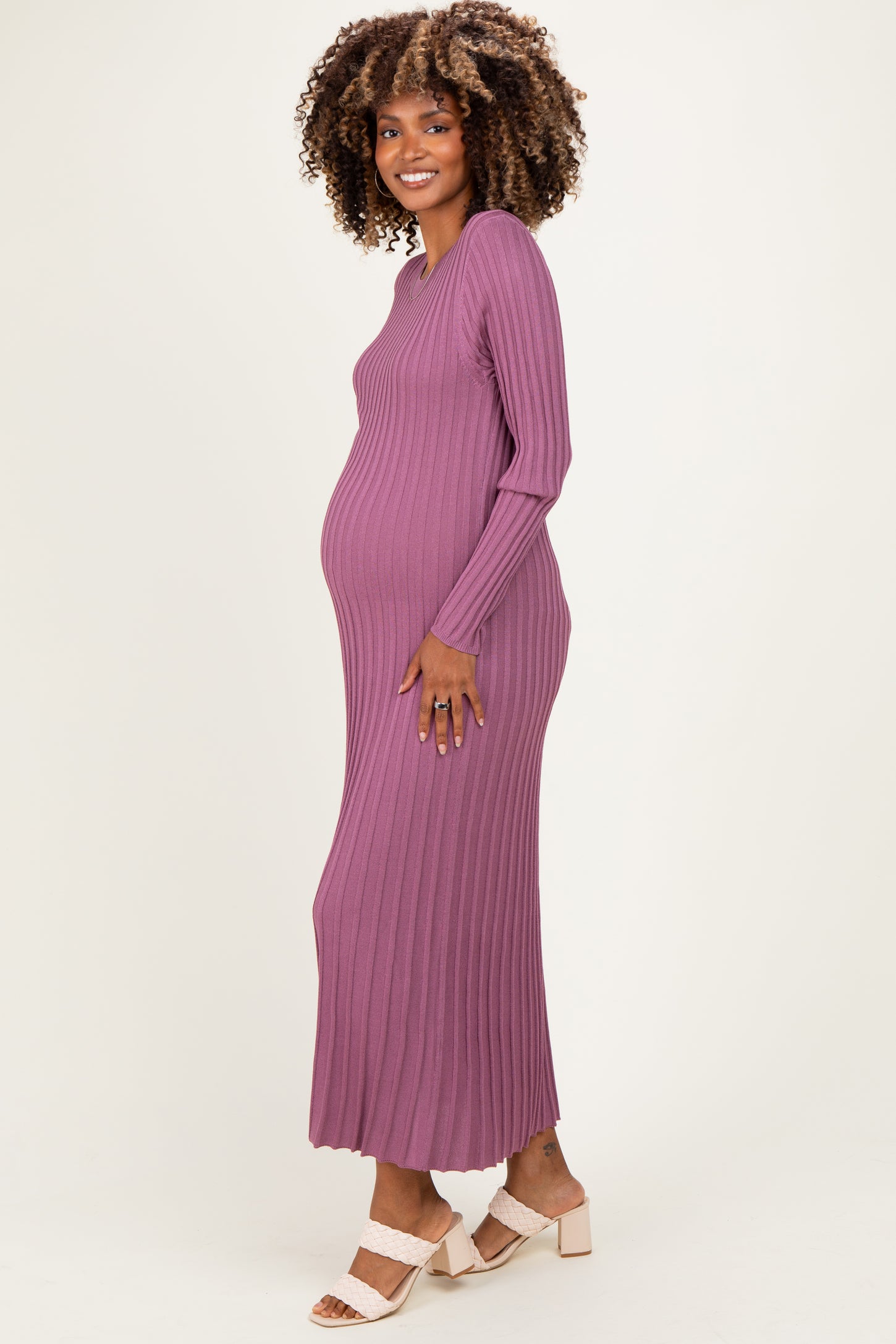 woman wearing a ribbed purple maternity maxi dress, showing her baby bump while smiling at the camera