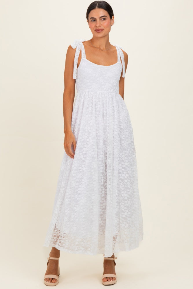 woman wearing a white lace maxi dress with tie shoulder straps and a tiered skirt