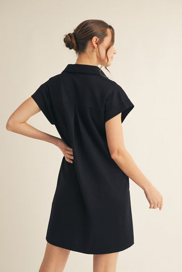 woman wearing a black short sleeve collared dress, shown from the back with a relaxed fit