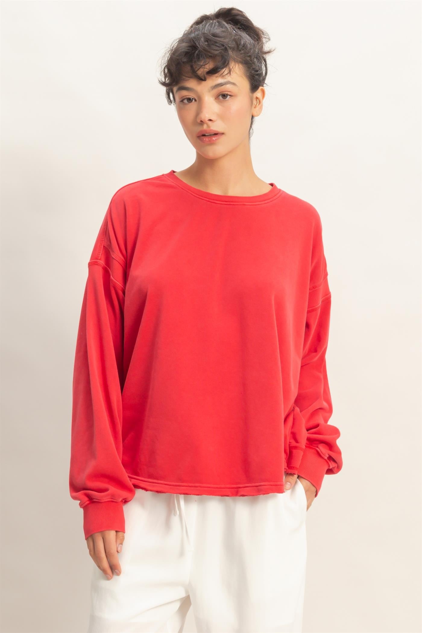 woman wearing a bright red long sleeve oversized sweatshirt with dropped shoulders and a relaxed fit