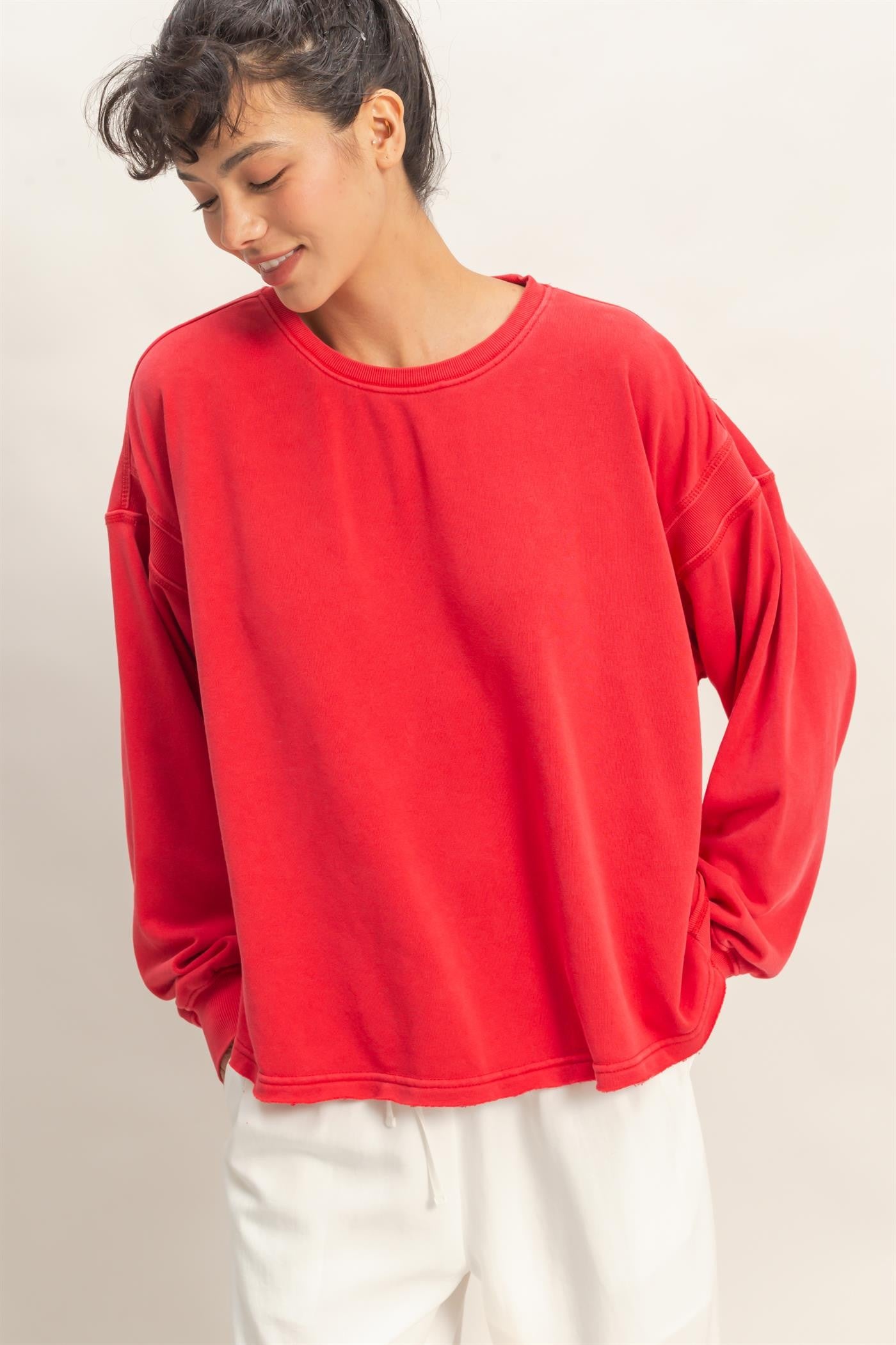 woman wearing a red oversized long sleeve sweatshirt with dropped shoulders and a relaxed fit