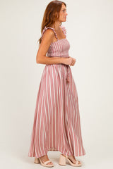 woman wearing a pink and white striped strapless maxi dress with ruffle straps and a tie waist