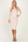 woman wearing a nude fitted midi dress with a sheer long sleeve top and strappy green heels