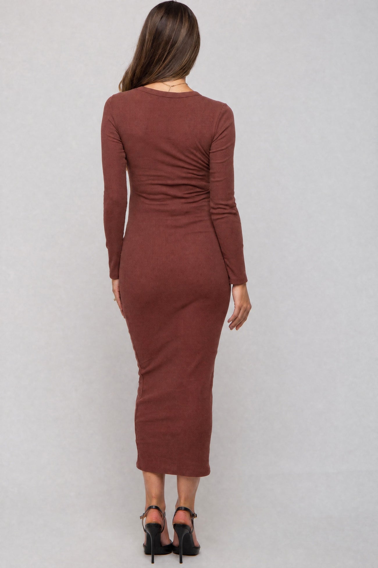 woman wearing a brown ribbed long sleeve maternity dress, showing a fitted silhouette from the back