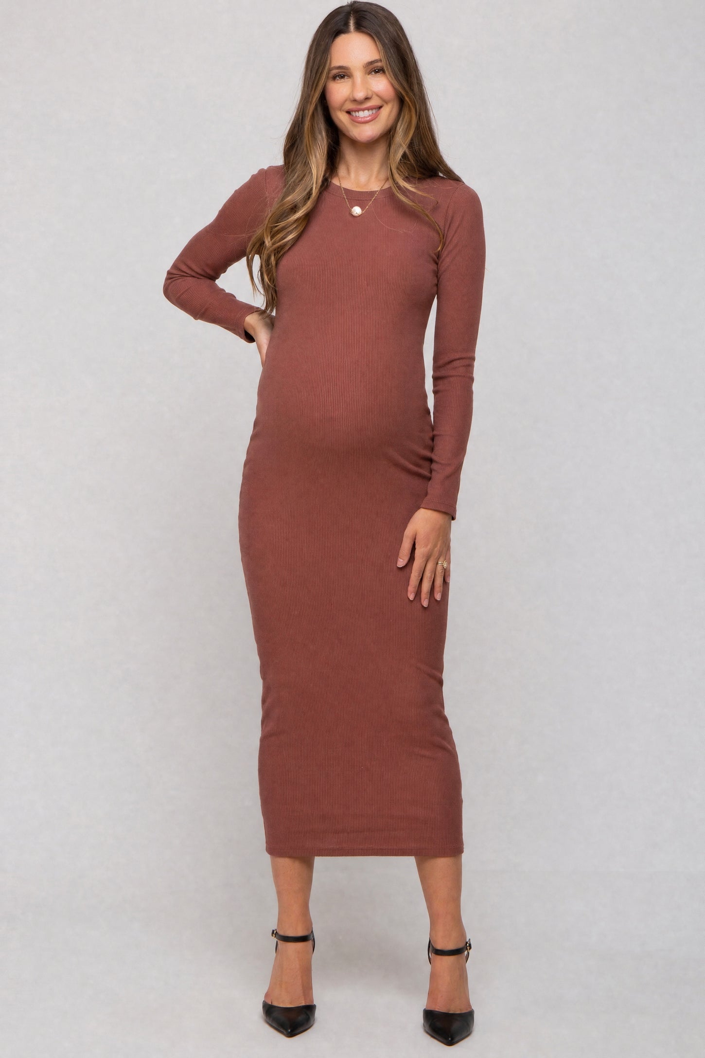 woman wearing a rust long sleeve ribbed maternity dress and showing her baby bump