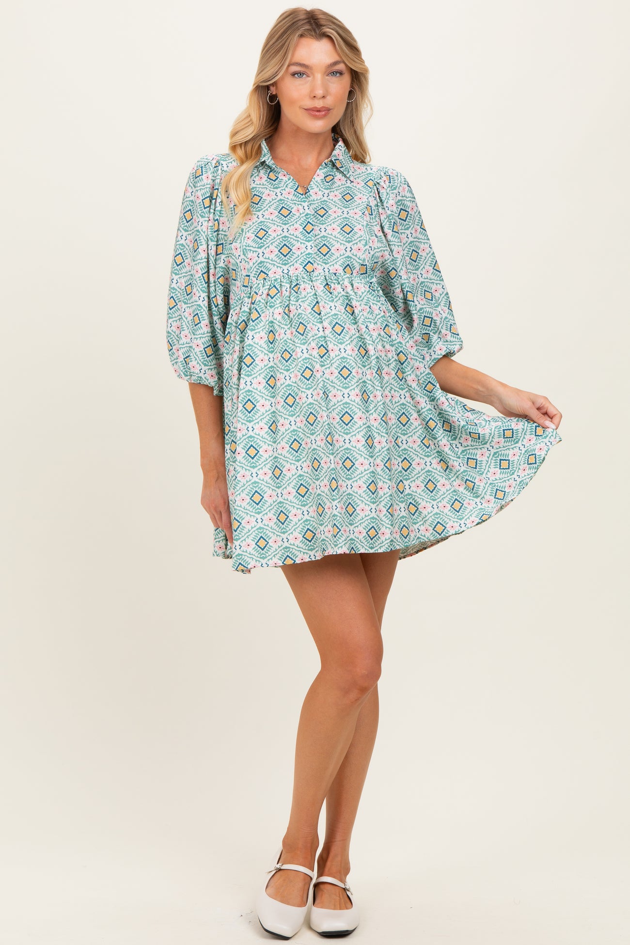 woman wearing a teal patterned maternity dress with balloon sleeves and a gathered waist, showcasing her baby bump