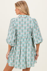 woman wearing a patterned turquoise maternity dress with puff sleeves and a loose fit, showing her baby bump from the back