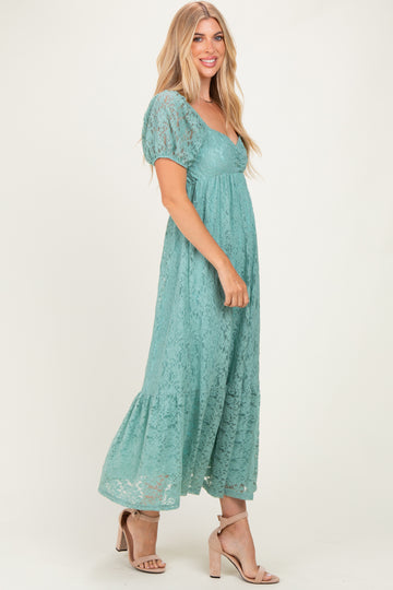 woman wearing a teal lace maxi dress with puff sleeves and a tiered hemline, standing in profile