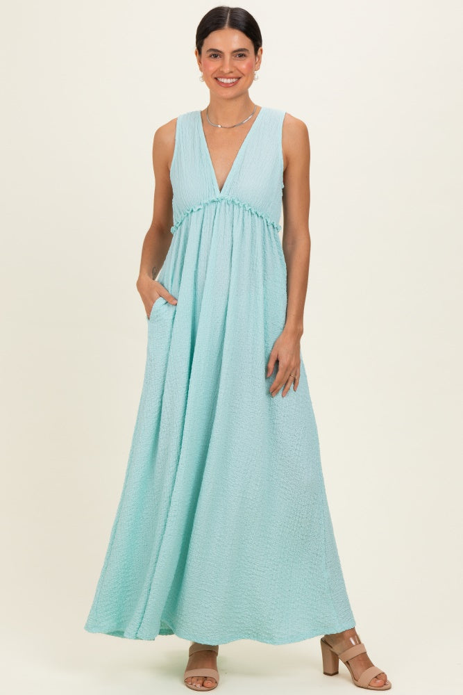 woman wearing a mint green maxi dress with a deep V-neck and side pockets
