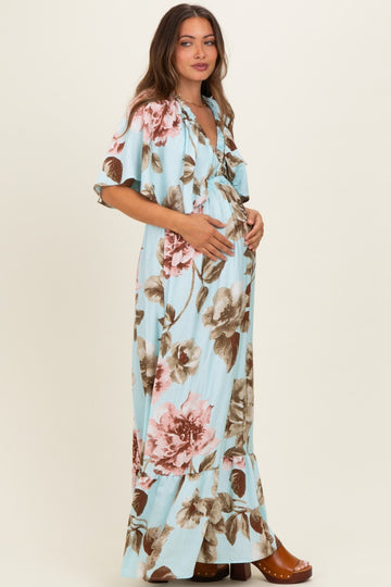 woman wearing a light blue floral maternity dress with ruffled hem and holding her baby bump