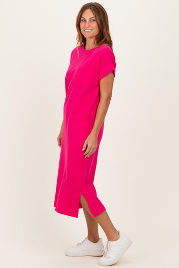 woman wearing a bright pink short sleeve midi dress with side slits and white sneakers