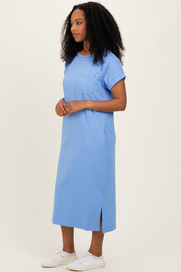 woman wearing a light blue short sleeve midi dress with a pocket and side slits, standing against a light background