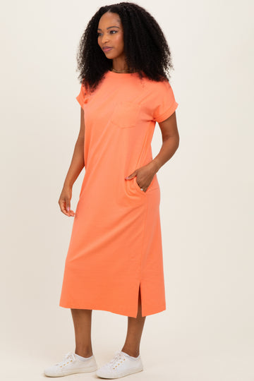 woman wearing a bright orange short sleeve pocket dress with side slits and white sneakers