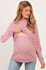 woman wearing a pink maternity hoodie with a front opening, revealing a baby bump while holding the fabric