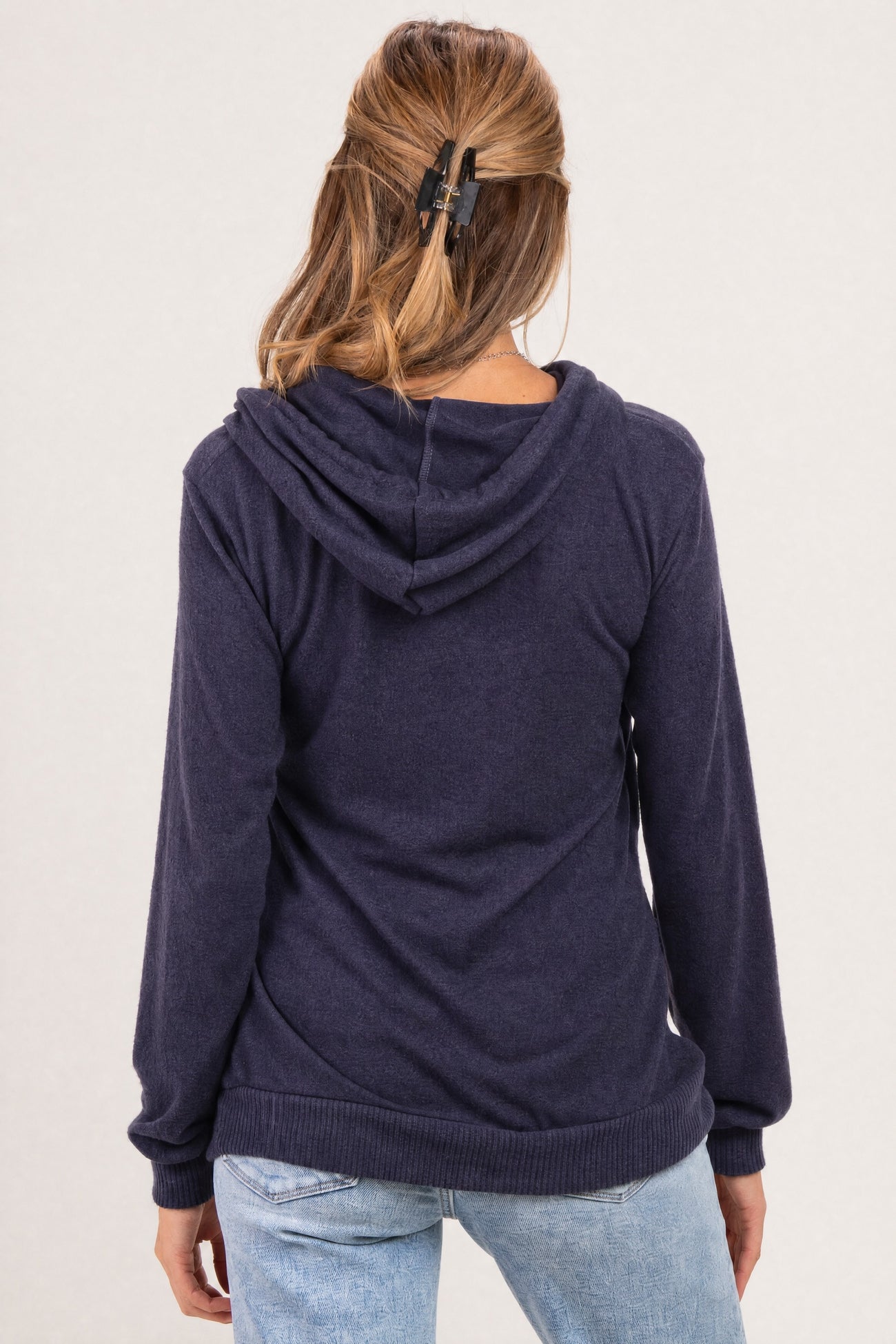 woman wearing a navy blue maternity hoodie with a drawstring hood and long sleeves, showing a relaxed fit from the back
