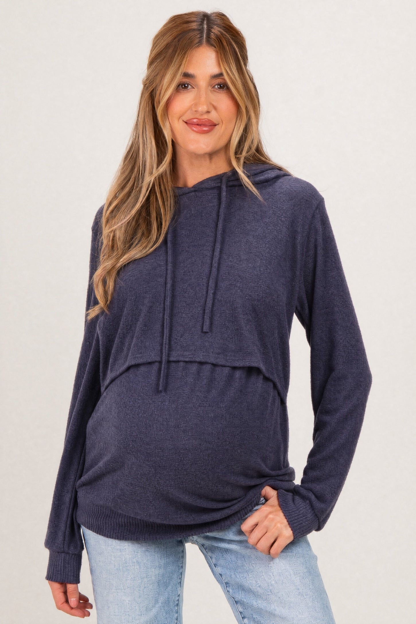 woman wearing a navy blue maternity hoodie with a cropped design and a visible baby bump