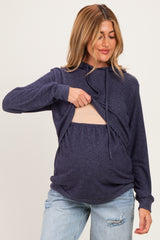 woman wearing a navy blue maternity hoodie with a cutout for nursing and showing her baby bump