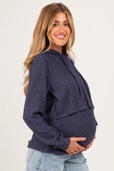 woman wearing a navy blue maternity hoodie with a layered design and holding her baby bump