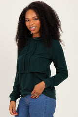woman wearing a dark green cropped hoodie with a drawstring and front pocket, paired with blue jeans