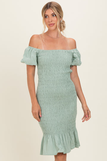 woman wearing a mint green off-the-shoulder smocked dress with puff sleeves and a ruffled hem