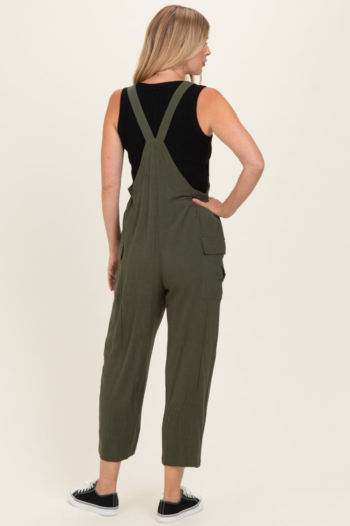 woman wearing an olive green overall jumpsuit with adjustable straps and side pockets, seen from the back