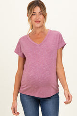 woman wearing a raspberry v-neck maternity top with rolled sleeves and a visible baby bump, paired with jeans